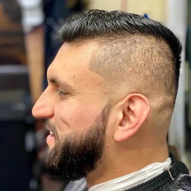 Combed-back side part with a faded beard
